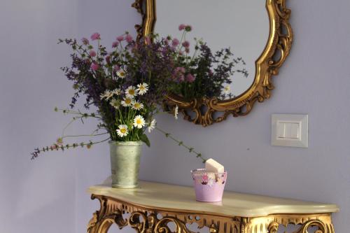 a vase of flowers on a table with a mirror at La Granda agrirelax in San Martino Alfieri
