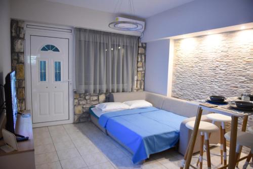a bedroom with a blue bed and a kitchen at Theoni's Seaside Apartment in Kalamata