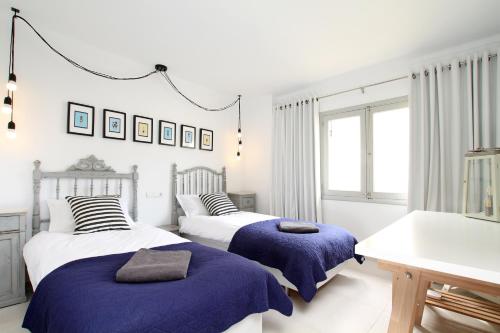 two beds in a white room with blue blankets at Casa Hugo in Pollença