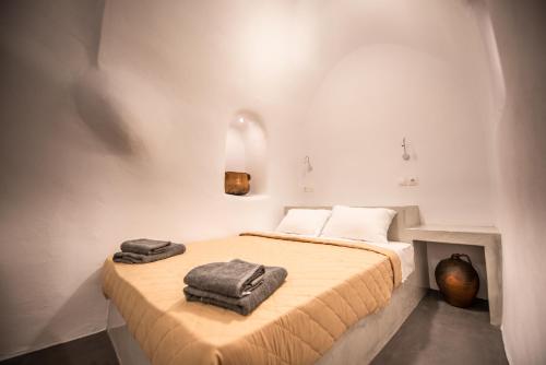 a bedroom with a bed with two towels on it at Caves 1880 in Oia