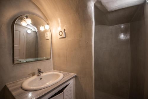 a bathroom with a sink and a mirror and a shower at Caves 1880 in Oia