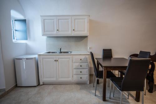 a kitchen with a sink and a table with chairs at Caves 1880 in Oia