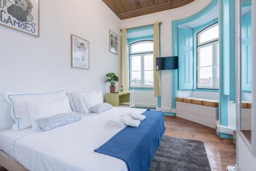 a bedroom with a large white bed with blue accents at C&O Guest House Lisbon in Lisbon