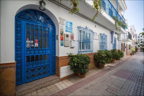 a blue and white building with a blue door at Hostal San Ramon in Marbella