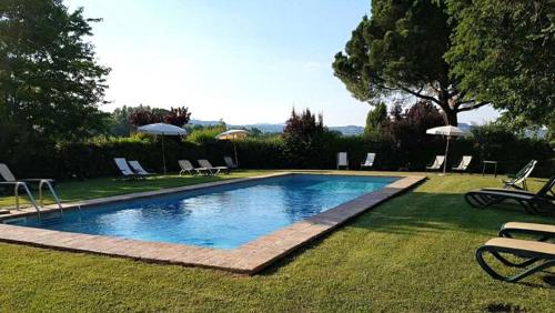 una piscina in un cortile con sedie e ombrelloni di Agriturismo Pian Del Tevere a Torgiano