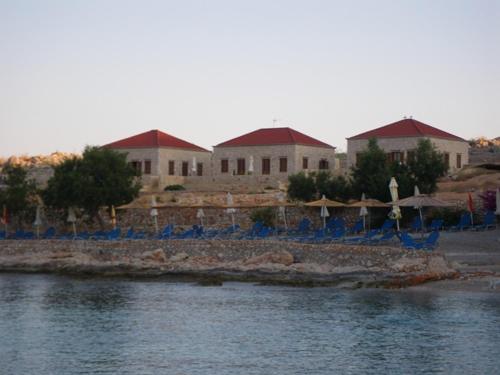 a beach with chairs and umbrellas next to the water at Cohili Villa in Halki