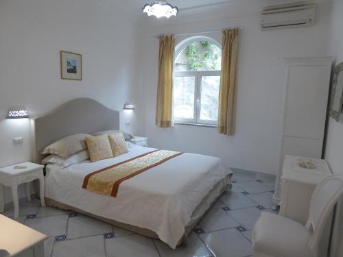a white bedroom with a bed and a window at Casa Lara 2 in Positano