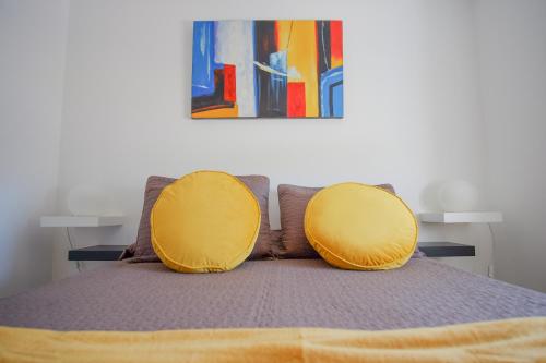 a bed with two yellow cushions on top of it at Apartamentos Pinhão in Lagos