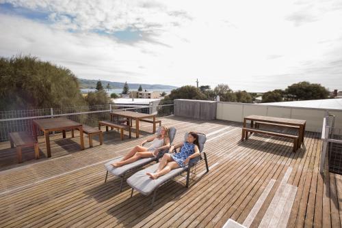 two girls sitting on a deck on a roof at YHA Apollo Bay Eco in Apollo Bay