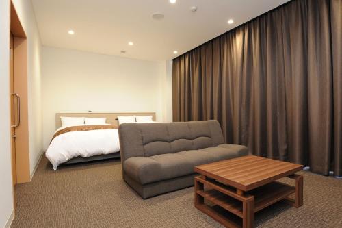 a bedroom with a bed and a couch and a table at Hotel Sunriver Shimanto in Shimanto