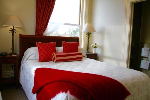 a bedroom with a bed with red pillows and a window at Merivale Manor in Christchurch