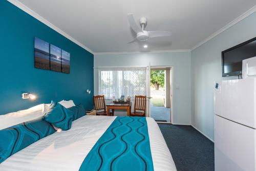 een slaapkamer met een groot bed met een blauwe muur bij Moore Park Beach Inn in North Coast
