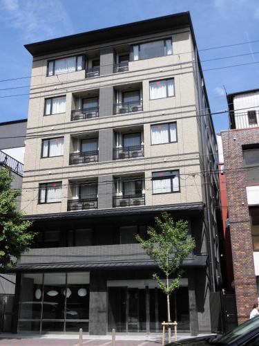a tall gray building with windows and a tree in front at Hotel IL Verde Kyoto in Kyoto