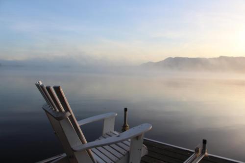 two chairs sitting on a deck overlooking the water at La Maison Jaune D'Eastman in Eastman