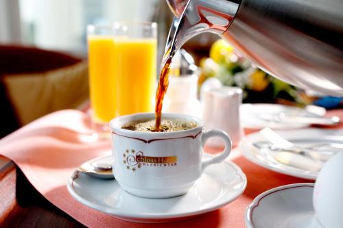 a person is pouring coffee into a cup on a table at Schloss Hotel Holzrichter in Nachrodt-Wiblingwerde