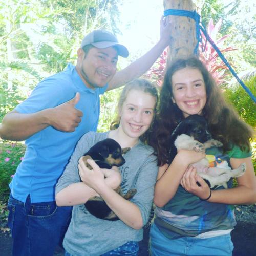 a man and two girls holding puppies in their arms at Hospedaje Bananas in Altagracia