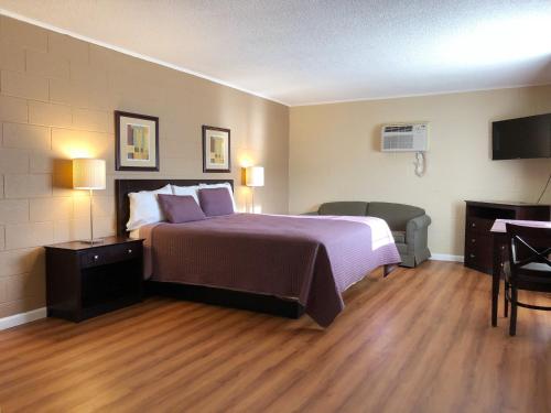 a hotel room with a large bed and a desk at Royal Inn and Suites in Hemet