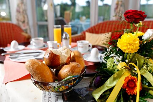a table with a bowl of bread and a vase of flowers at Schloss Hotel Holzrichter in Nachrodt-Wiblingwerde