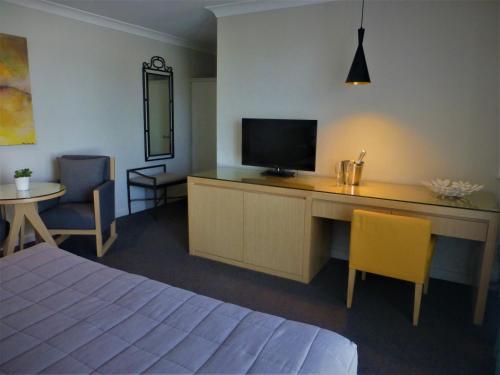 a bedroom with a desk with a television and chairs at Park Ridge Retreat in Gerringong