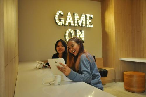 two women standing at a table with a tablet at YELLO Hotel Paskal Bandung in Bandung