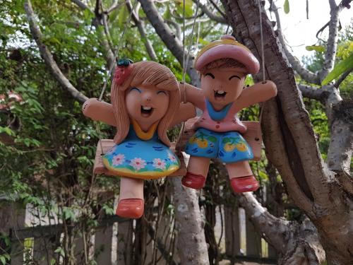 two wooden dolls hanging in a tree at Green Leaf Resort in Surin
