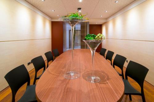 a wooden table with chairs and a vase with flowers on it at Hotel America Igualada in Igualada