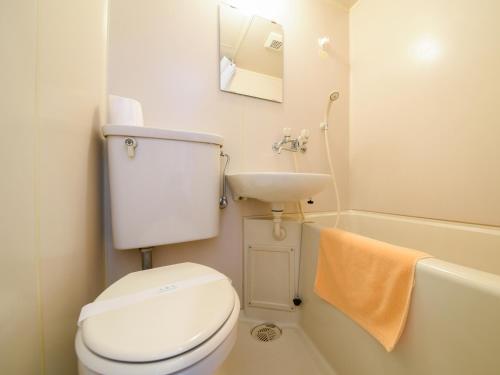 a white bathroom with a toilet and a sink at Business Hotel New Nagawajima in Fukuyama