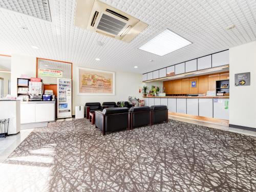 a waiting room with black chairs and a kitchen at Business Hotel New Nagawajima in Fukuyama