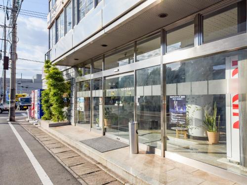 a building with glass windows on a city street at Business Hotel New Nagawajima in Fukuyama