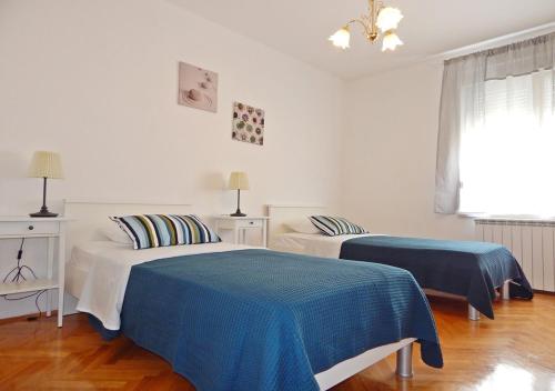 two beds in a white room with blue sheets at Apartments Katarina with swimming pool in Stobreč