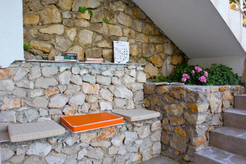 una panca arancione seduta su un muro di pietra di Apartments Gran Sasso a Ulcinj