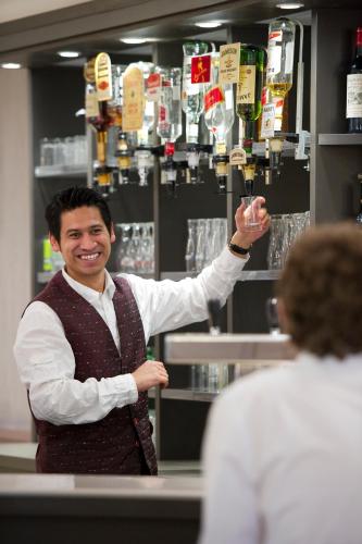 a man standing in a bar holding a wine glass at The Originals City, Hôtel Astoria Vatican, Lourdes in Lourdes