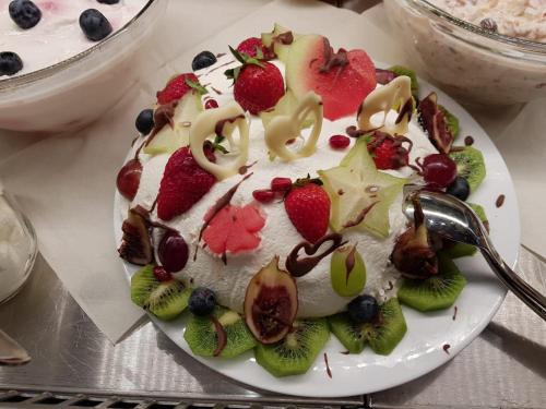 a cake with whipped cream and fruit on a plate at Vital Hotel an der Therme GmbH in Bad Windsheim