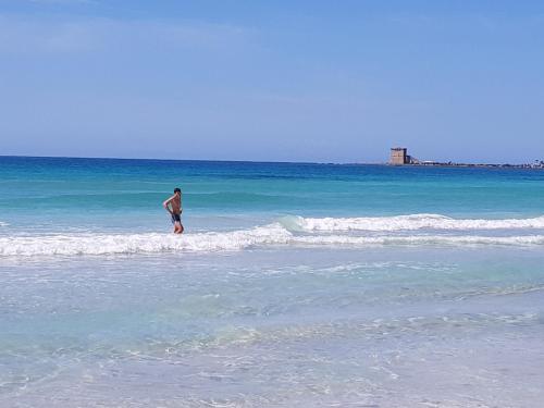 a man standing in the water at the beach at Villa Viola in Torre Lapillo