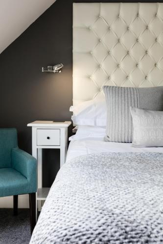 a bedroom with a white bed and a blue chair at Coast B&B in Bexhill