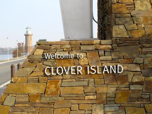 a stone wall with a sign that reads welcome to clover island at Clover Island Inn in Kennewick