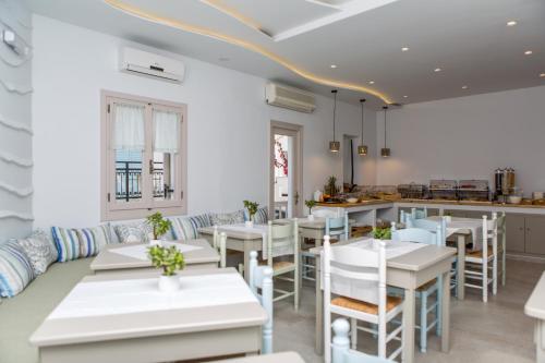 a restaurant with white tables and chairs and a counter at Argo Boutique Hotel in Naxos Chora