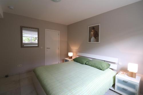 um quarto com uma cama com lençóis verdes e 2 candeeiros em Stefjes Holiday Home em Dilsen-Stokkem