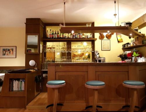 a bar with blue stools in a room at Hotel Pension Schweitzer in Silandro