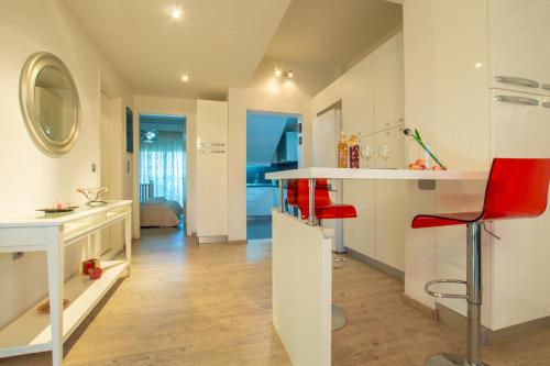 a kitchen with white counters and red chairs in a room at Rodia Apartments in Afantou