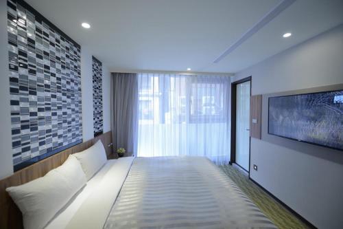 a bedroom with a bed with a tv on a wall at Ximen Hotel B in Taipei