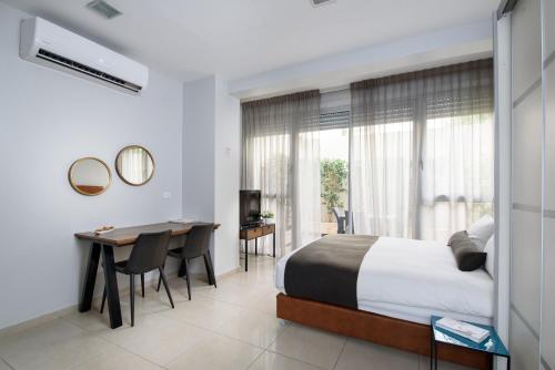 um quarto com uma cama, uma mesa e uma secretária em Sea Land Suites em Tel Aviv