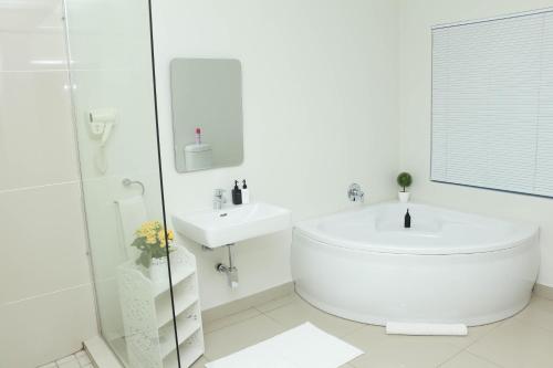 ein weißes Badezimmer mit einer Badewanne und einem Waschbecken in der Unterkunft The Milkwood Beach Apartments in Amanzimtoti
