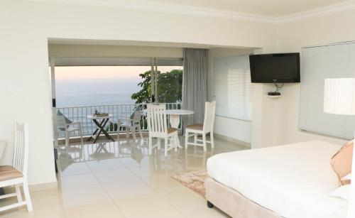 a bedroom with a bed and a balcony with the ocean at The Milkwood Beach Apartments in Amanzimtoti