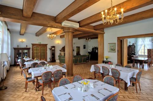 a dining room with white tables and chairs at Dwór w Bychowie in Bychowo