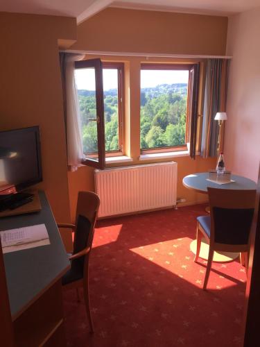 a room with a desk and a table and a window at Hotel Liebmann in Lassnitzhöhe