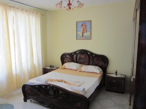 a bedroom with a bed with a wooden head board at Guest House Adi Doga in Berat