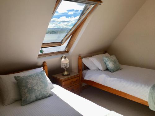 sypialnia na poddaszu z 2 łóżkami i oknem w obiekcie White Cottage B&B w mieście North Kessock