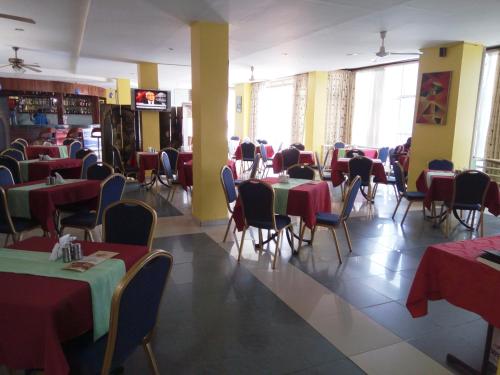 a dining room with tables and chairs with red and green tables at Aponye Hotel Kampala in Kampala