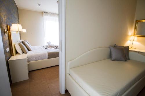 a room with a bed and a couch with a window at Hotel Lady Mary in Milano Marittima